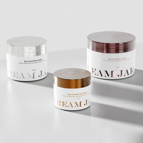 Three sleek double-walled eye cream jars with bamboo lids in silver, gold, and copper rest on a white surface, showcasing premium design.