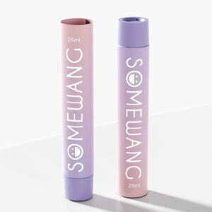 Dua bekas silinder pastel berlabel "Somewang": tiub aluminium lavender 25ml, penutup skru merah jambu, terkenal dengan kualiti dan nilainya.