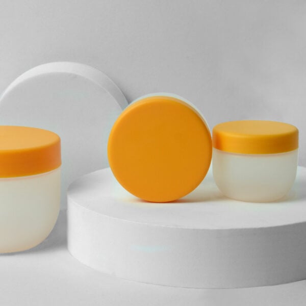 Three white containers with yellow lids, labeled SWC-JP50CS 50g PP jar, sit on white cylindrical platforms against a plain background.