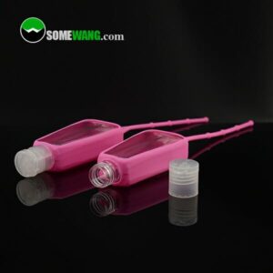 Yansıtıcı siyah yüzey üzerinde açılır kapaklı, üzerinde "somewang.com" logosu bulunan iki adet 2 ons/60 ml'lik boş el dezenfektanı plastik şişesi.