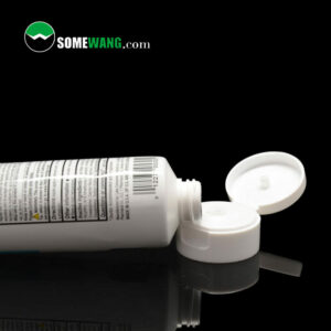 Một tuýp kem có nắp mở, có nhãn "somewang.com," trên bề mặt phản chiếu có nền tối, là Ống ABL có nắp lật màu trắng - Đường kính 25 mm - MOQ 30000 chiếc.