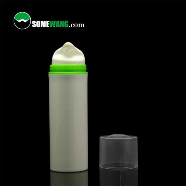 A green and white SWC-BPA10 Plastic PP cosmetic airless pump bottle with its cap off, against a black background, displaying the lotion pump head with a blob of cream.