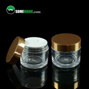 Two SWC-JBG50A 50g clear PETG cream jars with golden plating caps on a dark background, displaying the logo "somewang.com" at the top.