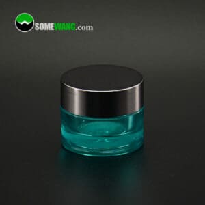 A teal SWC-JBG7A cream jar with a silver lid on a dark background.