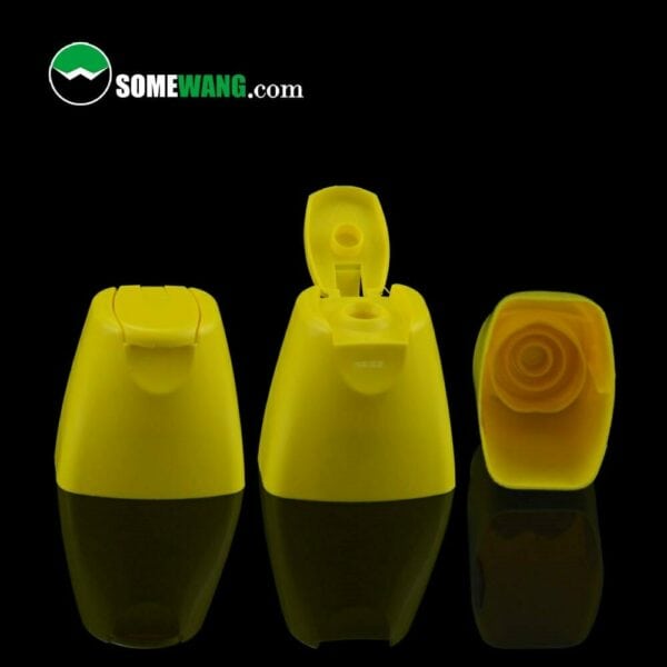 Three yellow plastic baby hair care bottle caps with a custom logo in different orientations on a dark background, showcasing top, front, and bottom views.