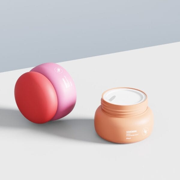 Dois potes de creme de cogumelo de 50 g — fechados em tom rosa-avermelhado e abertos em tom laranja — estão sobre uma superfície branca com fundo cinza claro.