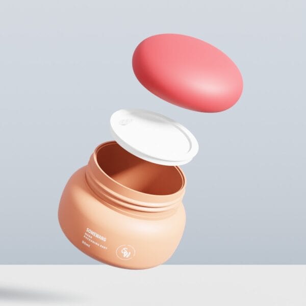 Um pote de creme de pêssego SWC-JP50SS com tampa interna branca e tampa externa rosa flutua sobre uma superfície clara em fundo cinza.