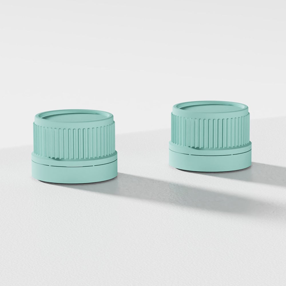 Two teal, ribbed 24mm child-resistant screw caps for bottles sit on a white surface, casting shadows.