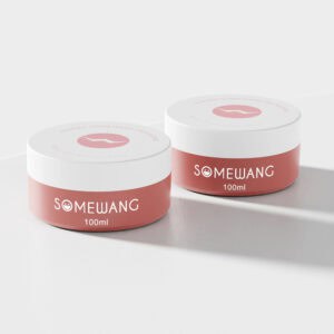 Dua balang kosmetik "SOMEWANG" 100ml merah jambu dengan penutup putih terletak dengan elegan pada permukaan putih, meniru reka bentuk bekas gel rambut yang lebih besar.