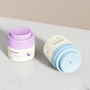 Dois potes de acrílico com bomba airless (15 ml/30 ml/50 ml) com tampas roxas ou azuis exibem um design cosmético elegante.