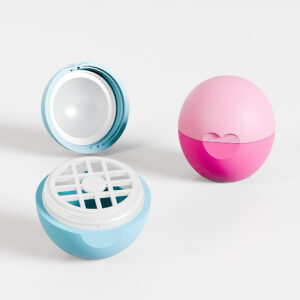 Two spherical containers: a closed pink one and an open light blue with a grid insert for lip balm, both styled as 7g egg-shaped spheres.