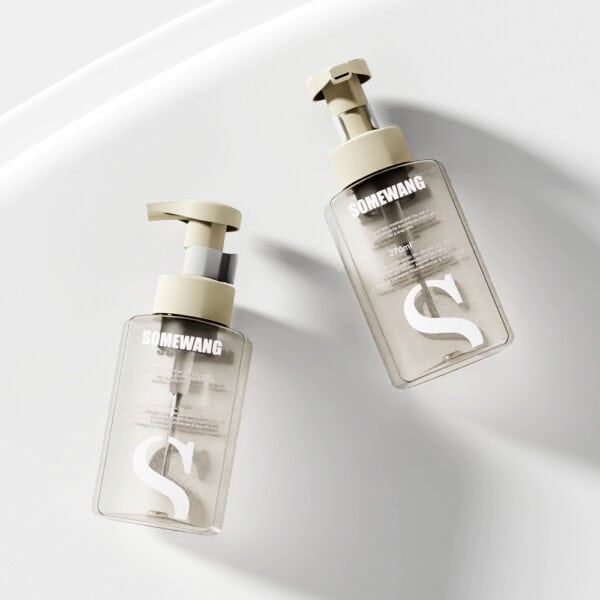 Two transparent "Wholesale Customized Round Shoulder Lotion Bottles" with beige caps elegantly sit on a white surface.