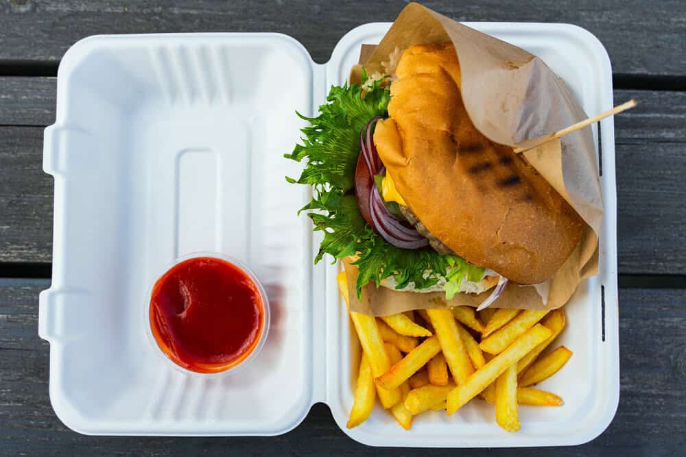 juicy hamburger french fries on styrofoam takeout box
