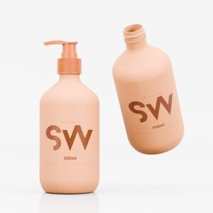 ขวด "SW" สีพีชขนาด 500 มล. สองขวด โดยขวดหนึ่งตั้งตรงและอีกขวดเอียง มาพร้อมบรรจุภัณฑ์ HDPE ที่ทันสมัยเพื่อการดูแลส่วนบุคคลที่อัปเกรด