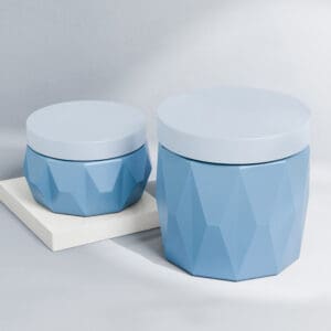 Dos tarros de diamantes de PP de pared simple geométricos azules de 400 ml para el cuidado de la piel de diferentes tamaños sobre una superficie blanca sobre un fondo gris claro.