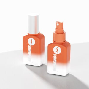 Two SOMEXMG PETG spray bottles in orange and white with a lightning bolt logo sit on a light surface; one capped, one open.