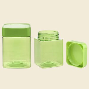 Drie doorschijnende groene 300 ml PET-plastic potten in vierkante vorm met bijpassende deksels, één geopend en gekanteld, op een lichte achtergrond.