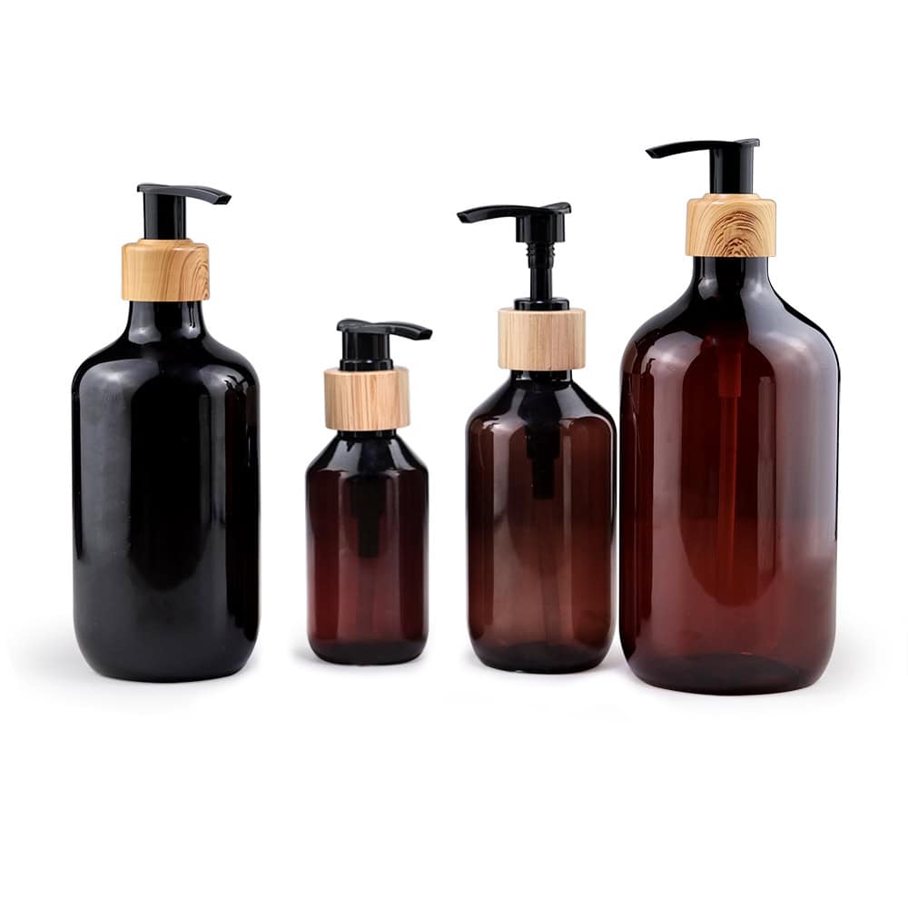 Four 24ml PET pharmaceutical bottles for personal care in black and amber with pump tops, isolated on a white background.