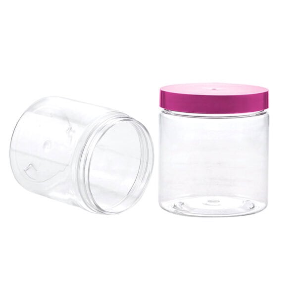 Two clear plastic jars, one lying lidless and the other upright with a pink lid, highlight our versatile 250ML PET Amber Cream Jar.