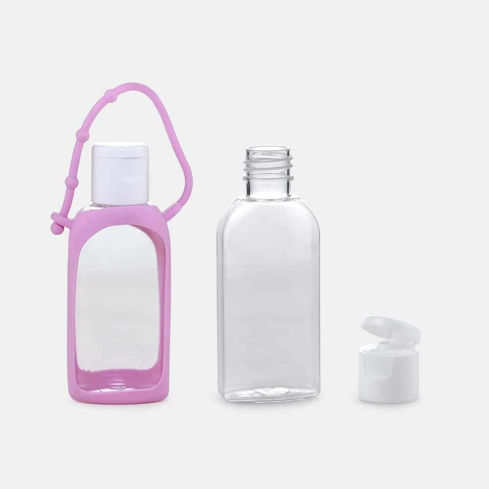 Tres diferentes botellas de desinfectante de manos vacías y transparentes de forma ovalada PET de 50 ml sobre un fondo blanco; uno encerrado en una funda de silicona rosa con un asa de transporte.