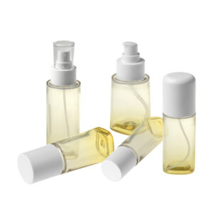 Cinco botellas PETG de 40ML/60ML/80ML/100ML para el cuidado de la piel con bombas, parcialmente llenas de líquido amarillo, aisladas sobre un fondo blanco.