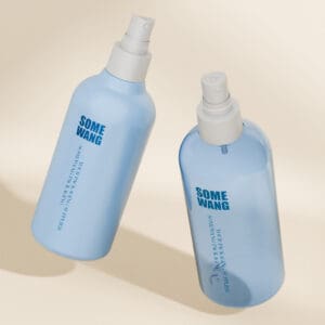 Due flaconi blu per la cura della pelle "SOME WANG" in PET da 240 ml con spruzzatori galleggiano su uno sfondo beige, ciascuno con un'angolazione diversa.