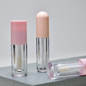 Lip Balm Stick and Lip Gloss Tubes with Pink Caps on Gray Surface.