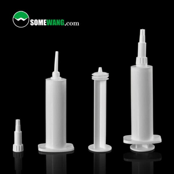 Four white plastic cartridges, resembling PP Syringe tubes, of various sizes stand vertically against a black background.