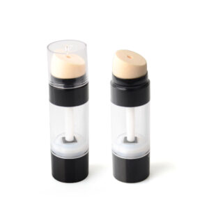 Twee doorzichtige cilindrische containers met zwarte bodem en beige sponsapplicators, waarvan één met dop. Beide kunnen concealer-markeerstiftsticks van 30 g zijn.
