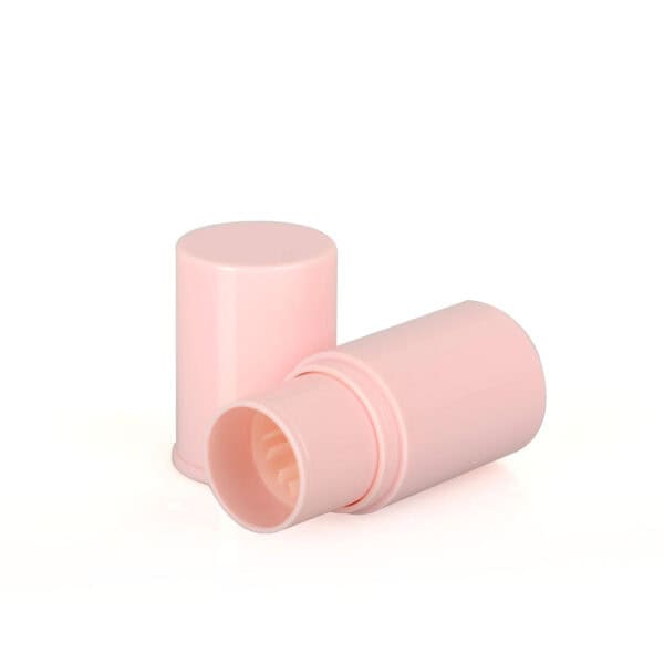 A pink cylindrical container, similar to an SWC-CFC006-4 concealer stick, with its lid off, lying on its side.