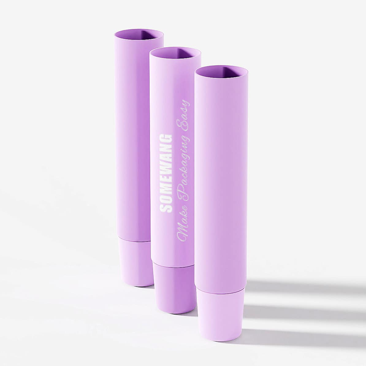 Three 15ML purple eye cream tubes with metal applicators stand upright on a light background, casting soft shadows.