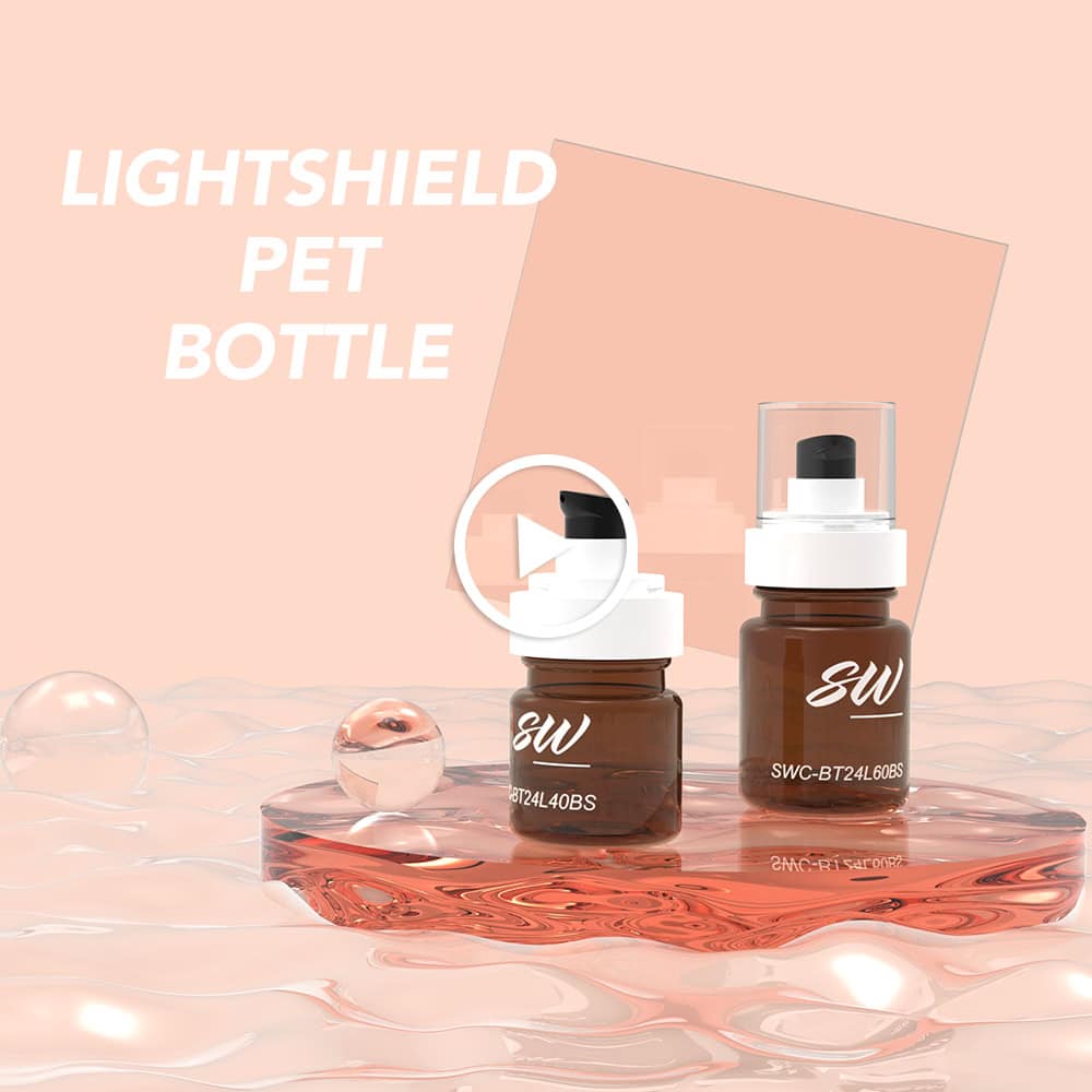 두 개의 호박색 펌프 병이 투명한 표면 위에 놓여 있고 그 위에 "LIGHTSHIELD PET BOTTLE"이라고 쓰여 있으며, 이미지 중앙에는 재생 버튼 아이콘이 있습니다.