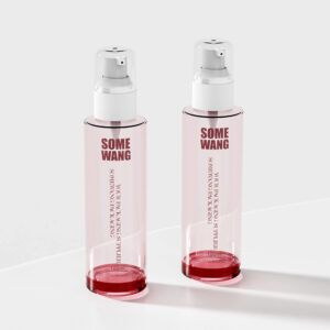 "Some Wang"이라는 라벨이 붙은 100ml 핑크색 유리병 두 개가 흰색 펌프와 함께 회색 배경의 흰색 표면 위에 세련되게 놓여 있습니다.