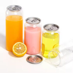 Tres latas de refresco de color naranja, rosa y amarillo de 250 ml o 350 ml sin abrir se encuentran junto a un limón en rodajas sobre una superficie blanca para mayor frescura.