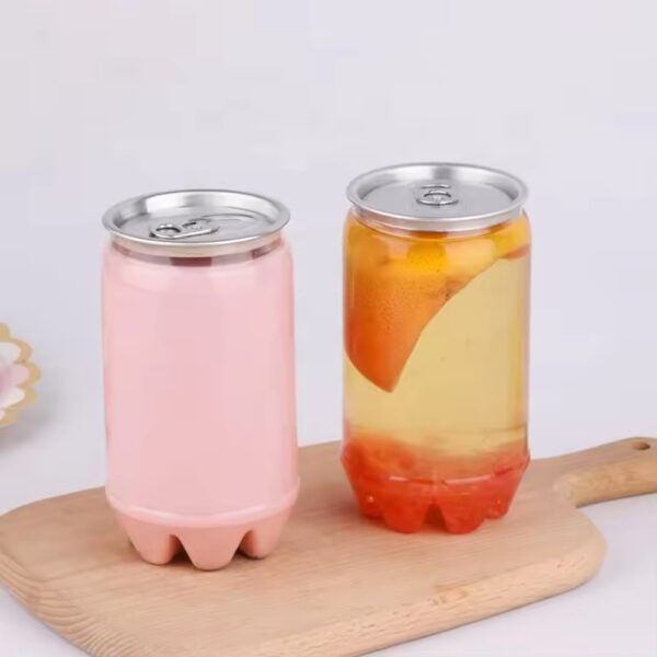 Two clear pop-top cans sit on a wooden board: one with pink liquid, the other with yellow liquid and fruit slices.