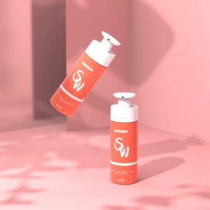 Dois frascos pump corais "SOMEWANG", um em pé e outro flutuando, sobre um fundo rosa com sombras suaves.