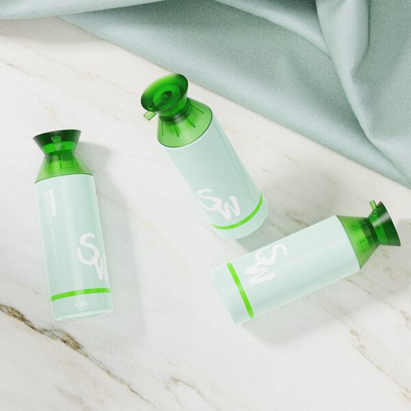 Three green-capped blue "SW" bottles sit on white marble beside a folded light green fabric.