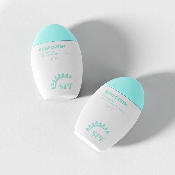 Dua botol pelindung matahari PE 50ml putih dengan penutup turquoise dan label "SPF" terletak di atas permukaan yang cerah, menghasilkan bayang-bayang lembut.