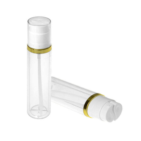 Dua botol pompa bening dengan tutup putih dan pita emas, satu tegak dan satu tergeletak.