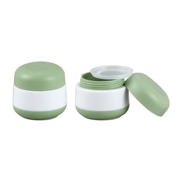 Two small green and white round jars, one open with a green interior, for use as customized 30g lotion containers.