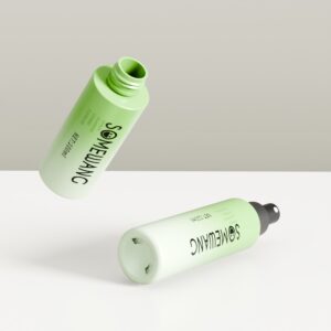Dua botol PET hijau (100–150ml) untuk losion/serum mengapung di latar belakang netral; satu terbuka, satu tertutup.