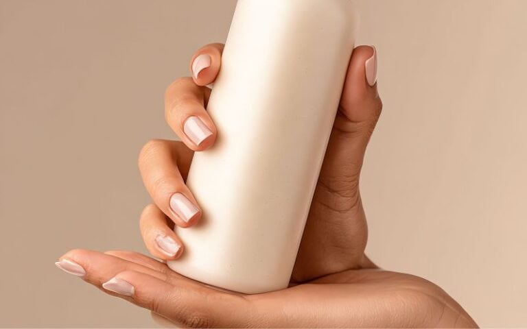 Close-up image of a hand holding a white skincare lotion bottle for clear, healthy skin.