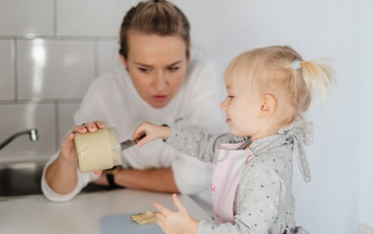 Young girl and woman engaging in cooking, demonstrating early culinary skills and safety awareness in a bright, modern kitchen environment.